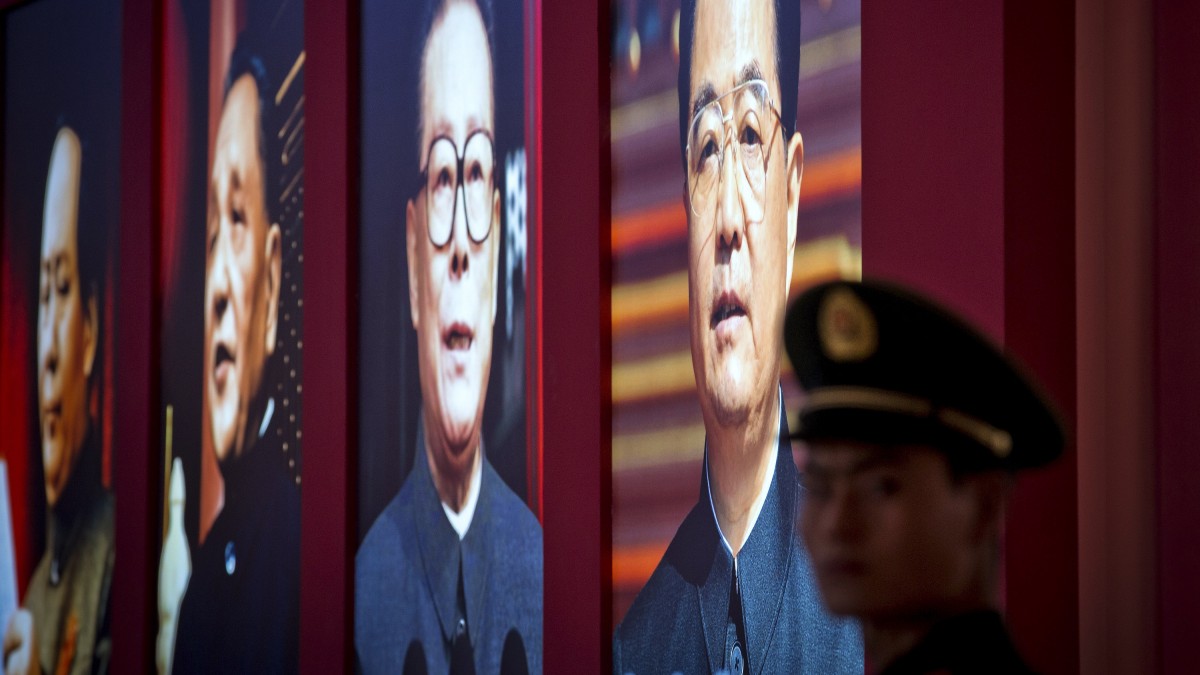 A Chinese paramilitary policeman stands watch next to a display showing four generations of Chinese leaders from right current President Hu Jintao, former President Jiang Zemin, paramount leaders Deng Xiaoping and Mao Zedong during an exhibition entitled 'Scientific Development and Splendid Achievements' held ahead of the 18th National Congress of the Communist Party of China (CPC) in Beijing Monday, Nov. 5, 2012. (AP Photo/Andy Wong)