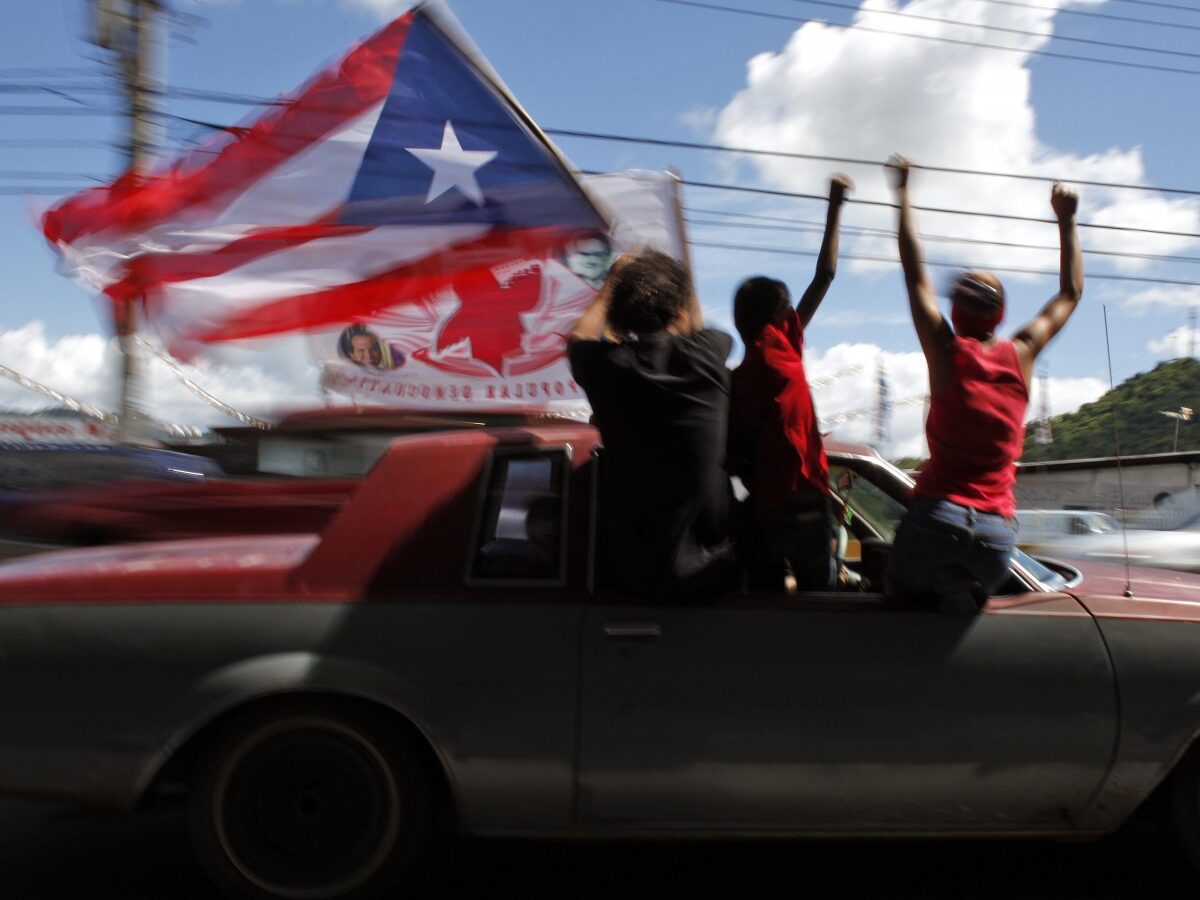 People ride atop a vehicle waving a Puerto Rican flag during elections in San Juan, Puerto Rico, Tuesday, Nov. 6, 2012. (AP Photo/Ricardo Arduengo)