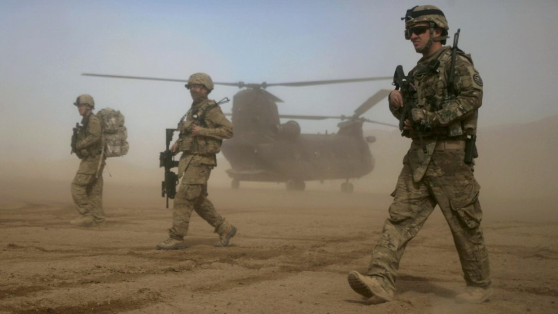 In this Saturday, Jan. 28, 2012 file photo, U.S. soldiers, part of the NATO-led International Security Assistance Force (ISAF) walks, as a U.S. Chinook helicopter is seen on the back ground near the place where the foundation of a hospital was laid in Shindand, Herat, west of Kabul, Afghanistan. (AP Photo/Hoshang Hashimi, File)