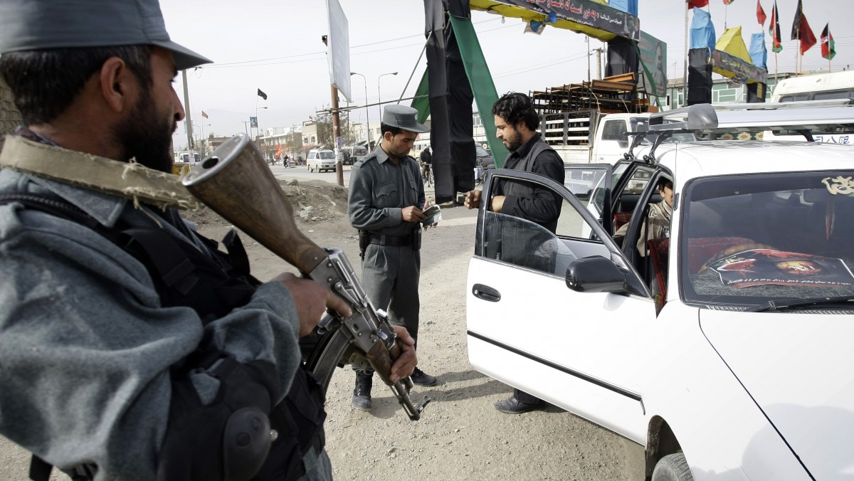 An Afghan policeman stands guard, left, as a police officers inspects the documents of a car at a checkpoint during an Ashoura commemoration in Kabul, Afghanistan, Wednesday, Nov. 21, 2012. (AP Photo/Musadeq Sadeq)