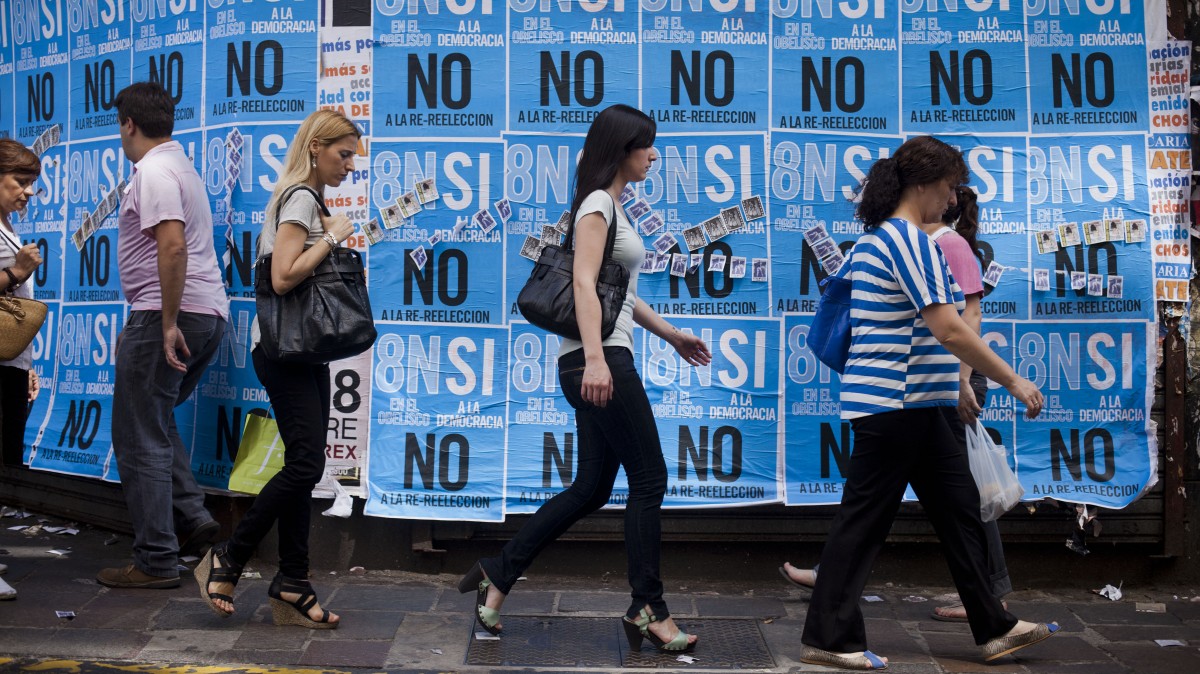People walk by posters promoting an anti-government march in Buenos Aires, Argentina, Wednesday, Nov. 7, 2012. People are using social networks instead of political parties to mobilize a massive march for Thursday against the leadership of Argentina's President Cristina Fernandez, mobilizing what they hope will be the largest anti-government protest the country has seen in more than a decade. The poster reads in Spanish "Yes to democracy, no to re-election." (AP Photo/Victor R. Caivano)