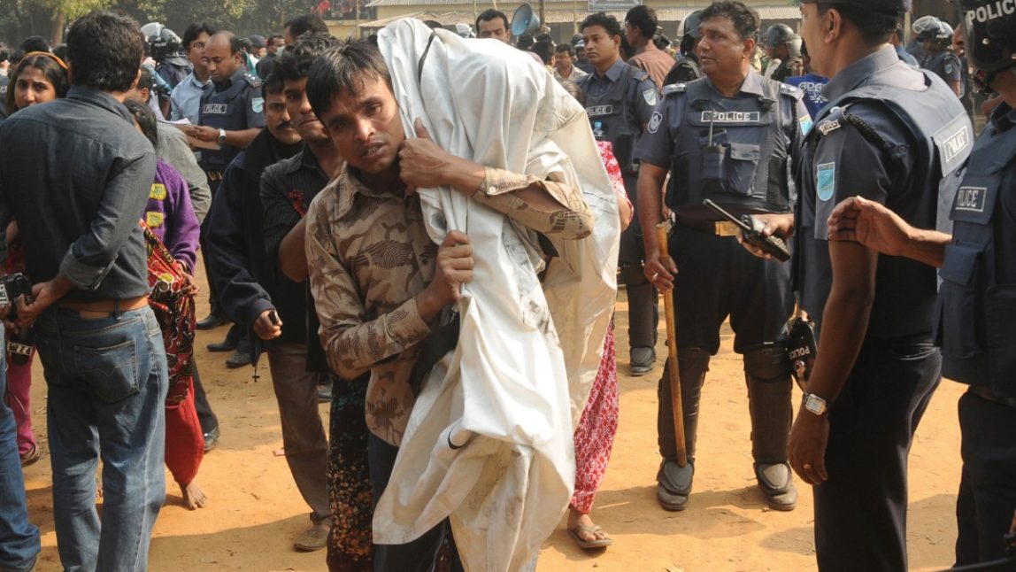 A Bangladeshi man carries his relative killed in a fire at a garment factory in the Savar neighborhood in Dhaka, Bangladesh, Sunday, Nov. 25, 2012. At least 112 people were killed late Saturday night in a fire that raced through the multi-story garment factory just outside of Bangladesh's capital, an official said Sunday. (AP Photo/Hasan Raza)