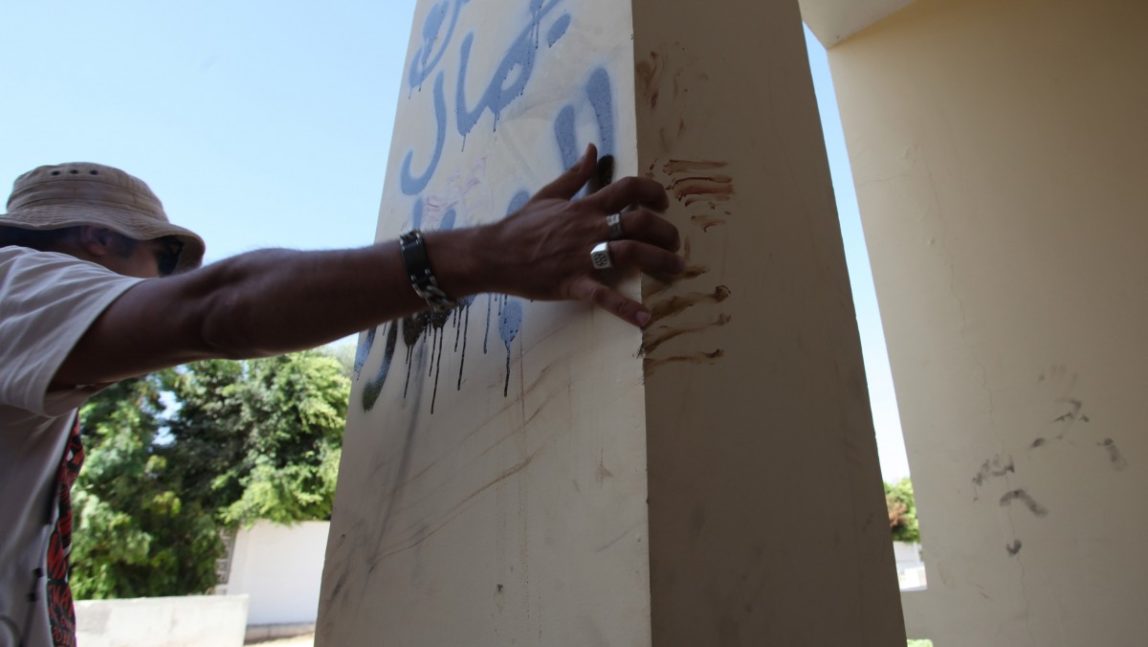 In this Thursday, Sept. 13, 2012 file photo, a Libyan man explains that the bloodstains on the column are from one the American staff members who grabbed the edge of the column while he was evacuated, after an attack that killed four Americans, including Ambassador Chris Stevens on the night of Tuesday, Sept. 11, 2012, in Benghazi, Libya. (AP Photo/Mohammad Hannon)