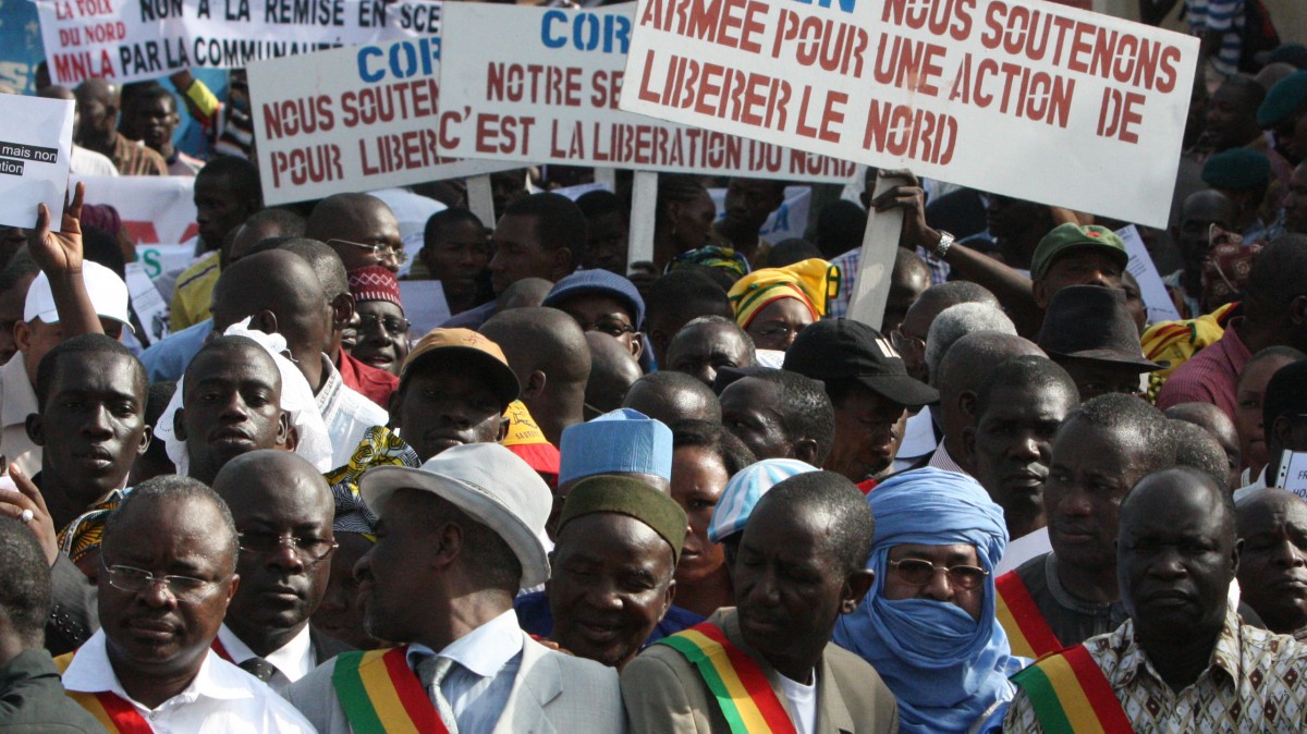 People originally from northern Mali carry signs reading 'We support army action to liberate the North,' as thousands of Malians, including elected officials, front, marched in support of foreign aid and military intervention to retake Mali's north from Islamist groups, in Bamako, Mali, Thursday, Oct. 11, 2012. (AP Photo/Harouna Traore)