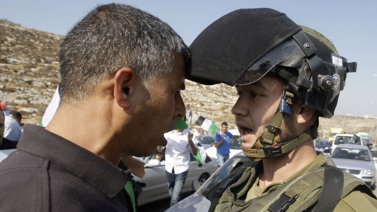 An Israeli soldier argues with a Palestinian man during a protest on the road 443 near the West Bank village of Beit Ur, west of Ramallah, Tuesday, Oct. 16, 2012. Palestinians blocked a road to protest against attacks by Jewish settlers on Palestinians and their property. (AP Photo/Nasser Shiyoukhi)