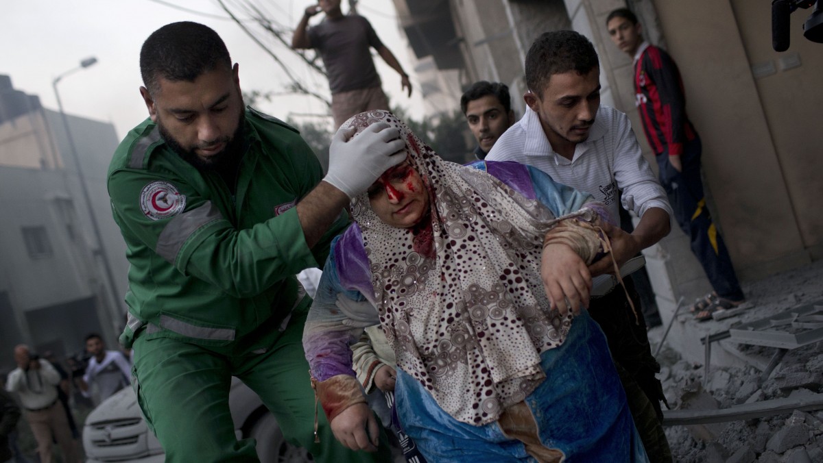 A Palestinian woman is helped after being injured during an Israeli forces strike on a soccer field next to her house in Gaza City, Monday, Nov. 19, 2012. (AP Photo/Bernat Armangue)