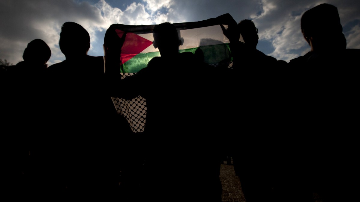 A Palestinian man holds a flag during a demonstration in support of the Palestinian statehood petition at the U.N. General Assembly near the Damascus gate in Jerusalem's Old City, Wednesday, Nov. 14, 2012. (AP Photo/Sebastian Scheiner)