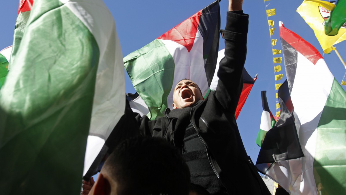 Surrounded by Palestinian flags a Palestinian chants slogans during a rally supporting the Palestinian UN bid for observer state status, in the West Bank city of Hebron, Thursday Nov. 29, 2012. (AP Photo/Nasser Shiyoukhi)