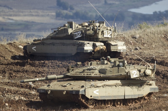 Israeli tanks, one in position, the other getting into a firing position in the Israeli-controlled Golan Heights overlooking the Syrian village of Bariqa, Monday, Nov. 12, 2012. (AP Photo/Ariel Schalit)