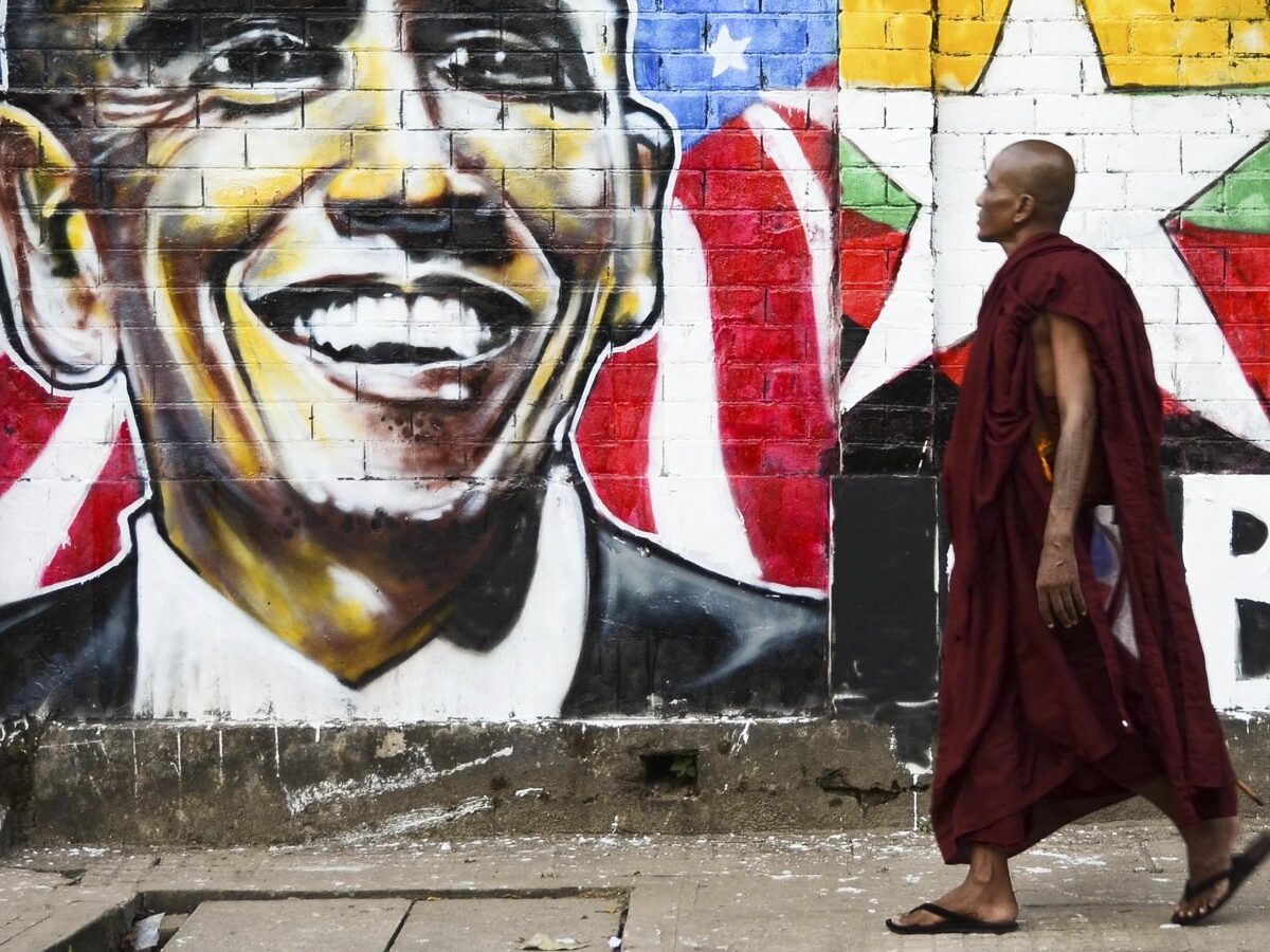 In this Sunday, Nov. 11, 2012 photo, a monk walks past a a wall painting created by graffiti artists to welcome U.S. President Barack Obama on a street in Yangon, Myanmar. Obama is scheduled to visit Myanmar later this week, the first visit by a U.S. president to the the one-time pariah nation, which is emerging from decades of military rule. (AP Photo/Aung Pyae)
