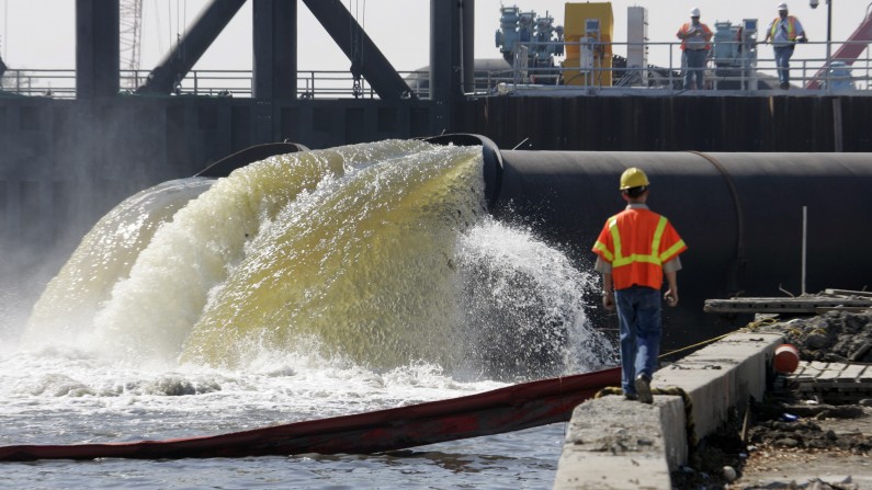 In this Saturday, March 10, 2007 file photo, Daren J. Eller watches as pumps put in place by the Army Corps of Engineers extract water from New Orleans' 17th Street Canal into Lake Pontchartrain in New Orleans. (AP Photo/Bill Haber, File)