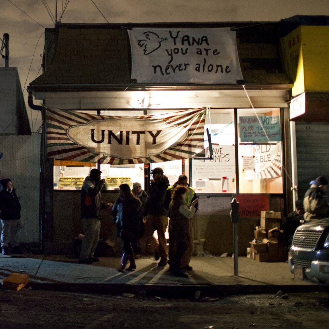 In this Thursday, Nov. 8, 2012 photo, at YANA (You are Never Alone), an outreach center that is currently housing Occupy Sandy, a volunteer aid organization in the Rockaway Park neighborhood of the Queens borough of New York, volunteers and those seeking assistance stand outside. (AP Photo/Craig Ruttle)