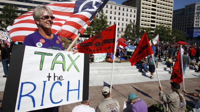 In this Oct. 6, 2011 file photo, Carol Gay, of Brick, N.J., holds a sign saying "Tax the Rich," as several groups including the Peoples Uprisings, October 2011 Coalition, and Occupy DC, "occupy" Freedom Plaza in Washington. (AP Photo/Jacquelyn Martin, File)