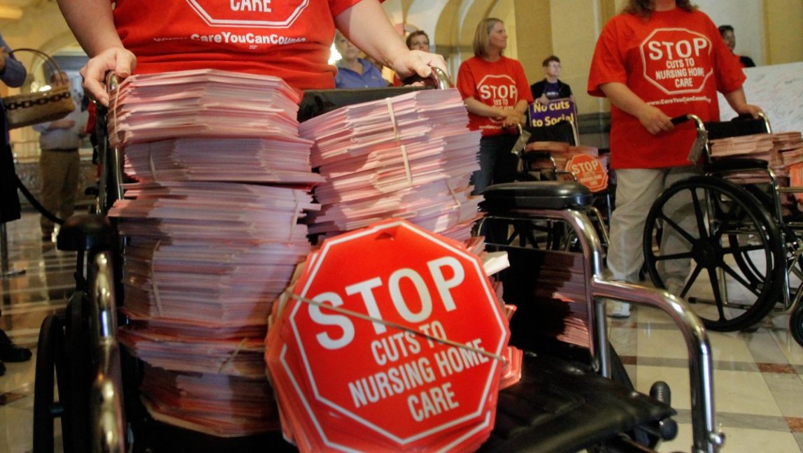 In this photo taken May 18, 2011, members of the the Health Care Council of Illinois use wheelchairs to deliver signs to stop cuts to Medicaid to Illinois Gov. Pat Quinn. (AP Photo/Seth Perlman)