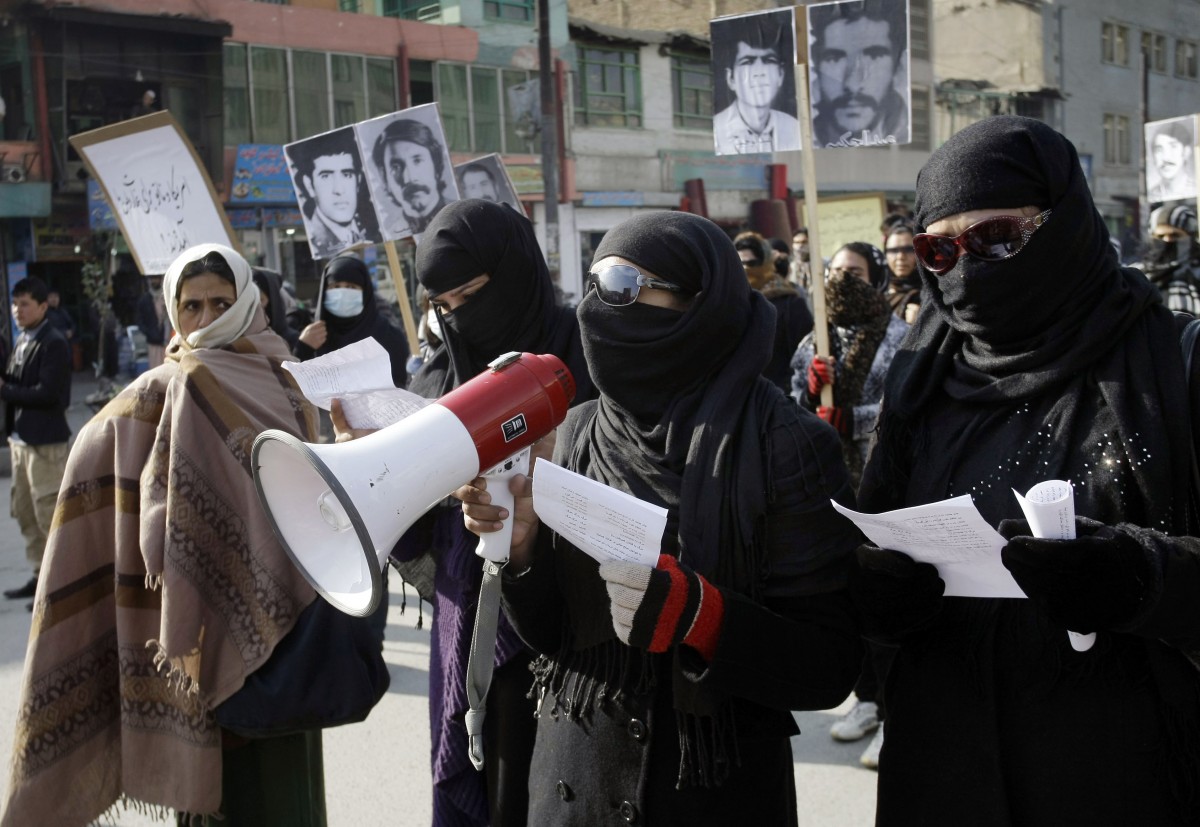 An Afghan protester speaks on a loudspeaker as others hold portraits of Afghans who were killed in the past three decades of war and violence, during a demonstration for human rights in Kabul, Afghanistan, Monday, Dec. 10, 2012. (AP Photo/Musadeq Sadeq)
