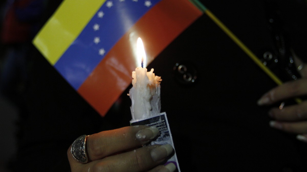 A person holds a candle and a Venezuelan flag during a vigil for Venezuela's President Hugo Chavez in La Paz, Bolivia, Monday Dec. 10, 2012. (AP Photo/Juan Karita)