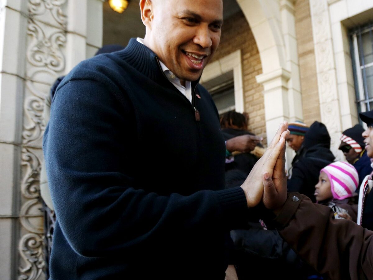 In this Friday, Nov. 9, 2012 file photo, Newark Mayor Cory Booker, left, greets 13-year-old Blonbzell Taylor outside of Clinton Hill Community Resource Center, where residents impacted by Superstorm Sandy received clothing donations in Newark, N.J. (AP Photo/Julio Cortez)