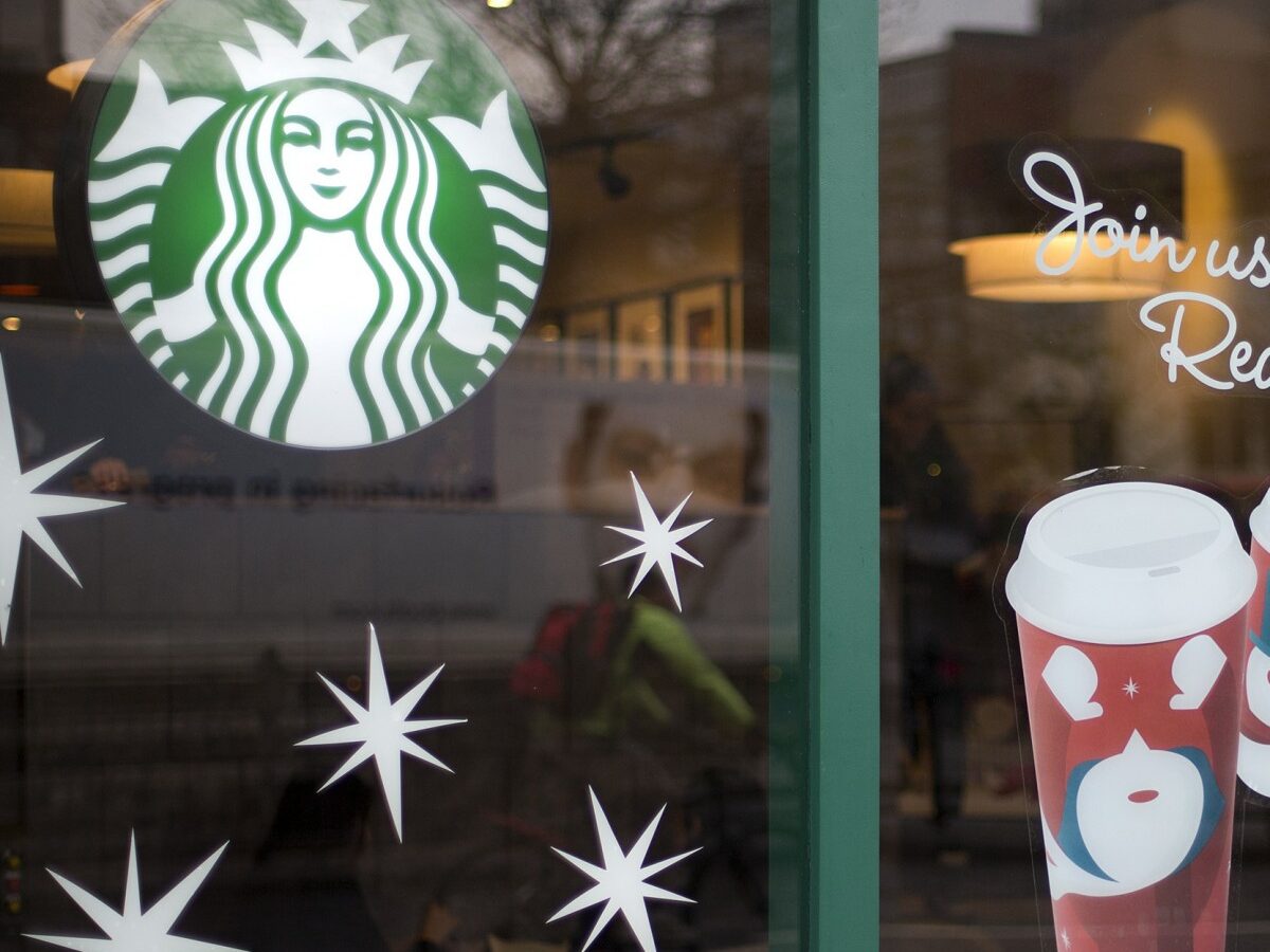 A man walks out of a Starbucks coffee cafe holding a drink in west London, Monday, Dec. 3, 2012. (AP Photo/Alastair Grant)