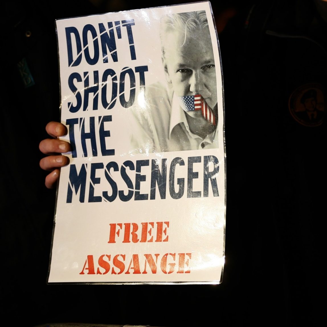 A supporter holds a banner as he waits for Julian Assange, founder of WikiLeaks to speak to the media and members of the public from a balcony at the Ecuadorian Embassy in London, Thursday, Dec. 20, 2012. (AP Photo/Kirsty Wigglesworth)