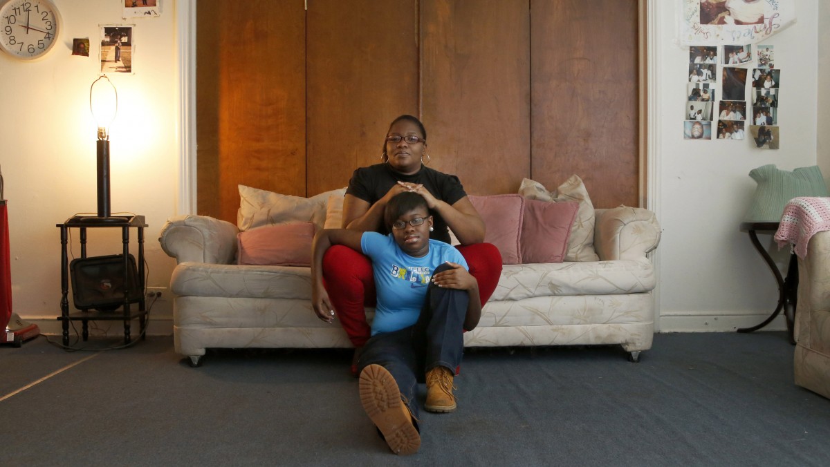 In this Wednesday, Dec. 26, 2012 photo, Bobby McComb sits on the sofa with her 14 year-old daughter, Cerria, at their home in the Auburn-Gresham neighborhood of Chicago's South Side. (AP Photo/Charles Rex Arbogast)