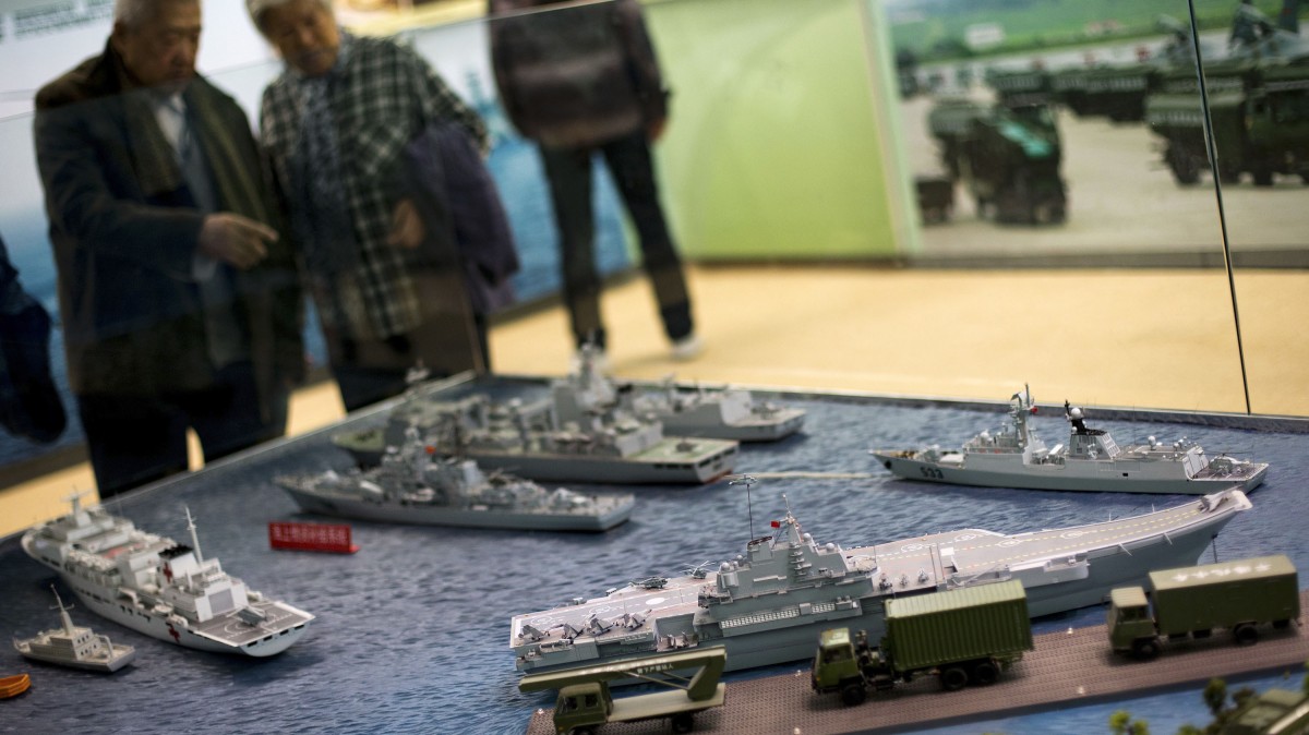 Visitors look at a scale model of Chinese aircraft carrier Liaoning, bottom right, among the naval ships on display at the military section of an exhibition entitled 'Scientific Development and Splendid Achievements' held ahead of the 18th National Congress of the Communist Party of China (CPC) in Beijing Monday, Nov. 5, 2012. (AP Photo/Andy Wong)