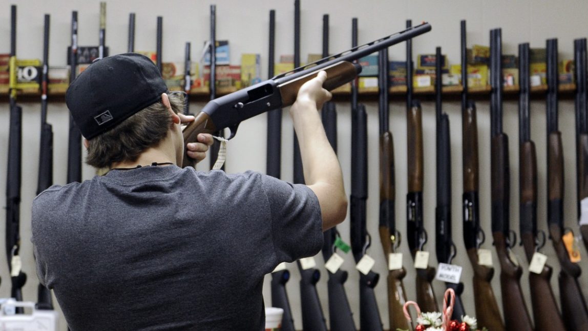 In this photo taken Wednesday, Dec. 19, 2012, a customer checks out a shotgun at Burdett & Son Outdoor Adventure Shop in College Station, Texas. (AP Photo/Pat Sullivan)