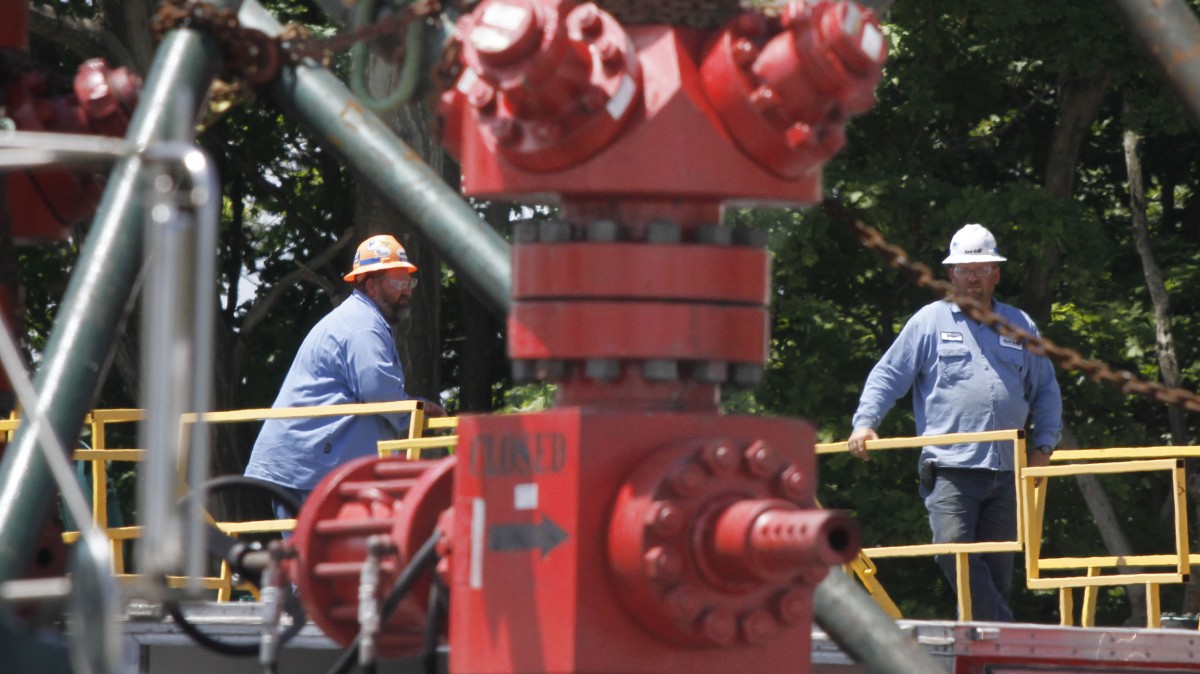 In this July 27, 2011 file photo, a pair of workers stand behind the top of a pump where the hydraulic fracturing process in the Marcellus Shale layer to release natural gas was underway at a Range Resources site in Claysville, Pa. (AP Photo/Keith Srakocic, File)