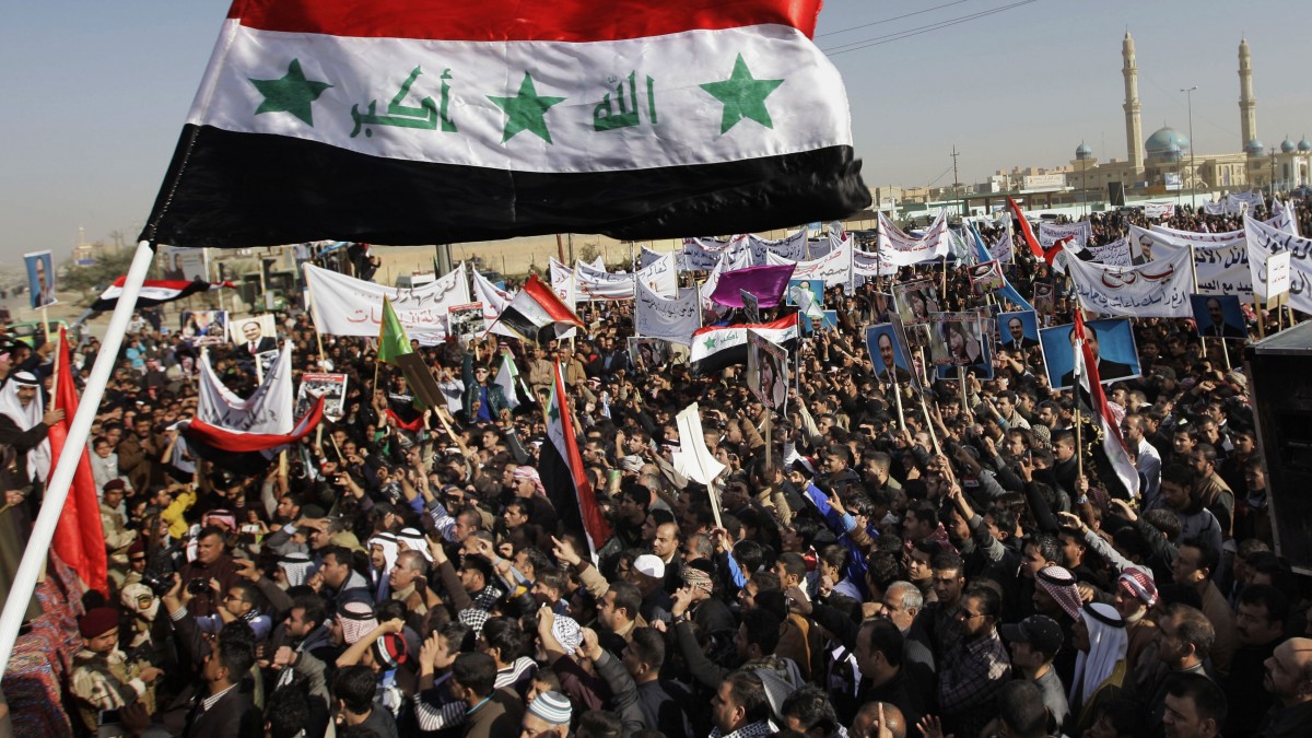 Protesters chant slogans against the Iraq's Shiite-led government as they wave national flags and hold posters of Sunni Finance Minister Rafia al-Issawi during a demonstration in Fallujah, 40 miles (65 kilometers) west of Baghdad, Iraq, Sunday, Dec. 23, 2012. (AP Photo/ Khalid Mohammed)