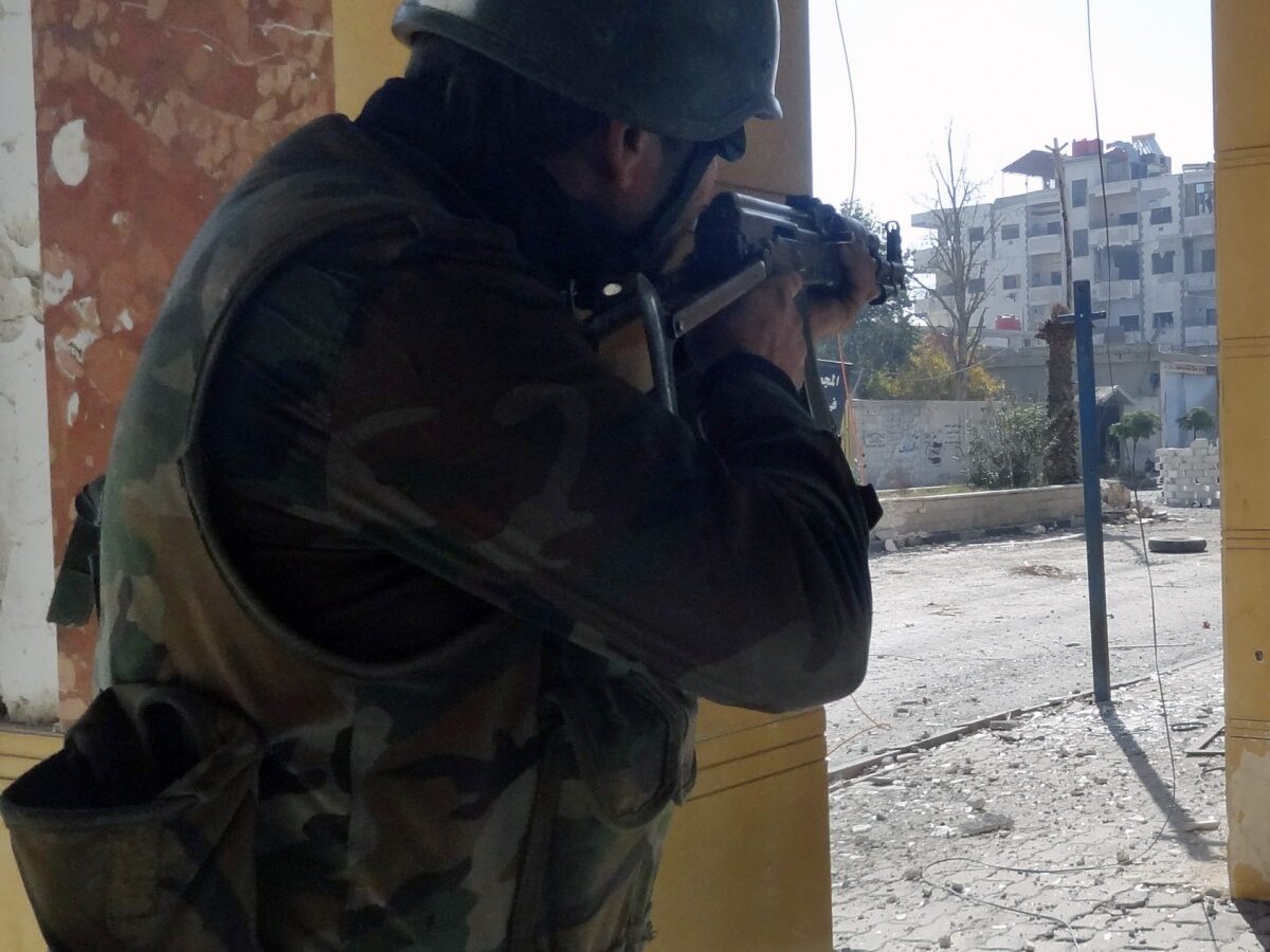 In this Sunday, Dec. 2, 2012 photo released by the Syrian official news agency SANA, a Syrian soldier aims his rifle at free Syrian Army fighters during clashes in the Damascus suburb of Daraya, Syria. (AP Photo/SANA)