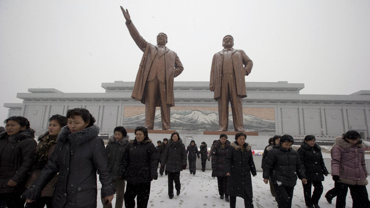 North Koreans leave after laying flowers to show respect to the statues of late North Korean leaders Kim Il Sung at left and Kim Jong Il at Mansu Hill as it snows in Pyongyang, North Korea, Friday, Dec. 21, 2012. (AP Photo/Ng Han Guan)