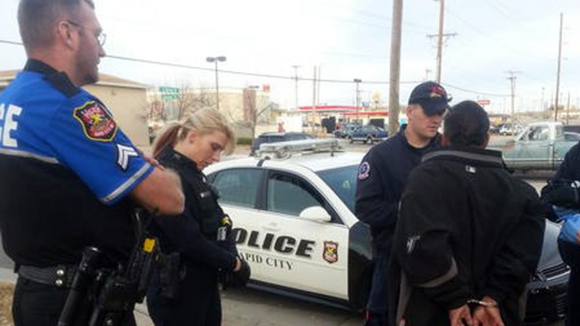 In this Nov. 21, 2012 photo provided by the Rapid City Police Department Officer Ron Terviel, left, and Officer Carmen Visian wait while paramedics check a hit-and-run suspect during a Tweetalong in Rapid City, S.D. On a virtual ridealongs on Twitter, or Tweetalongs, officers post regular updates to Twitter about what they are seeing as they perform their normal on-duty routine. (AP Photo/Rapid City Police, Tarah Heupel)