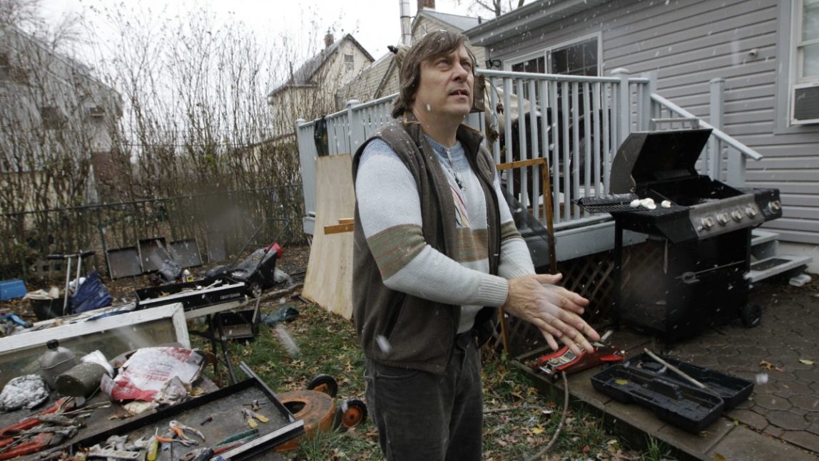 In this Wednesday, Nov. 7, 2012 file photo, Frank Hlavaty rubs his hands together for warmth as snow starts to fall near his house in Little Ferry, N.J., flooded by Superstorm Sandy. (AP Photo/Kathy Willens, File)