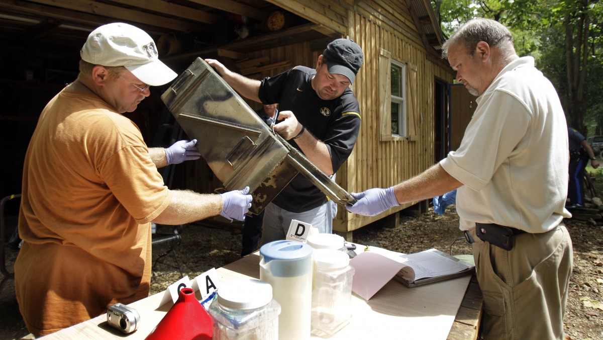 In this Sept. 2, 2010 file photo, Franklin County Detective Jason Grellner, center, sorts through evidence with Detective Darryl Balleydier, left, and reserve Officer Mark Holguin during a raid of a suspected meth house in Gerald, Mo. (AP Photo/Jeff Roberson, File)