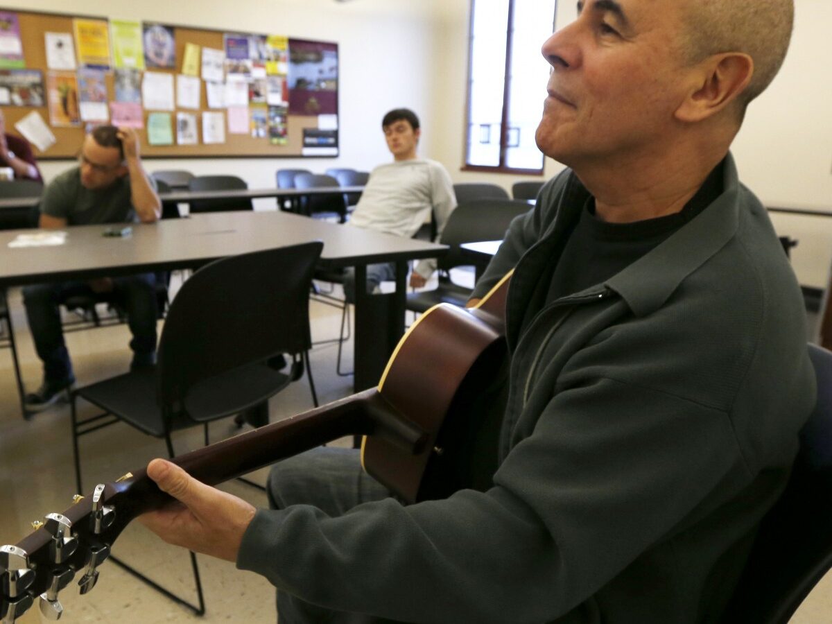 In this Oct. 10, 2012, photo, musician Julio Fernandez holds a guitar during a class session at Montclair State University in Montclair, N.J. (AP Photo/Julio Cortez)