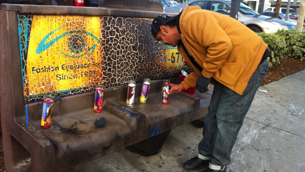 Phil Furtado places candles on a burned city bus bench in Los Angeles on Thursday, Dec. 27,2012. (AP Photo/Greg Risling)