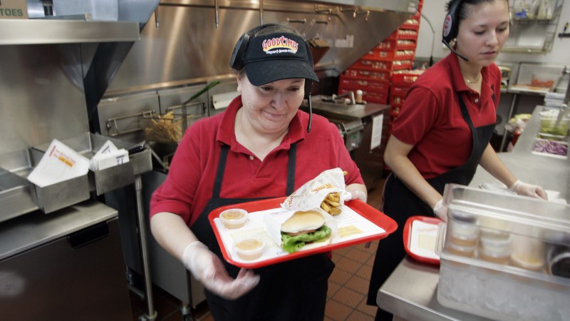 Ernestina Gevara carries a tray full of food out of the kitchen as Jura Martinez, right, prepares food at the Good Times fast food restaurant in Thornton, Colo., Tuesday, Oct. 24, 2006. (AP Photo/Jack Dempsey)