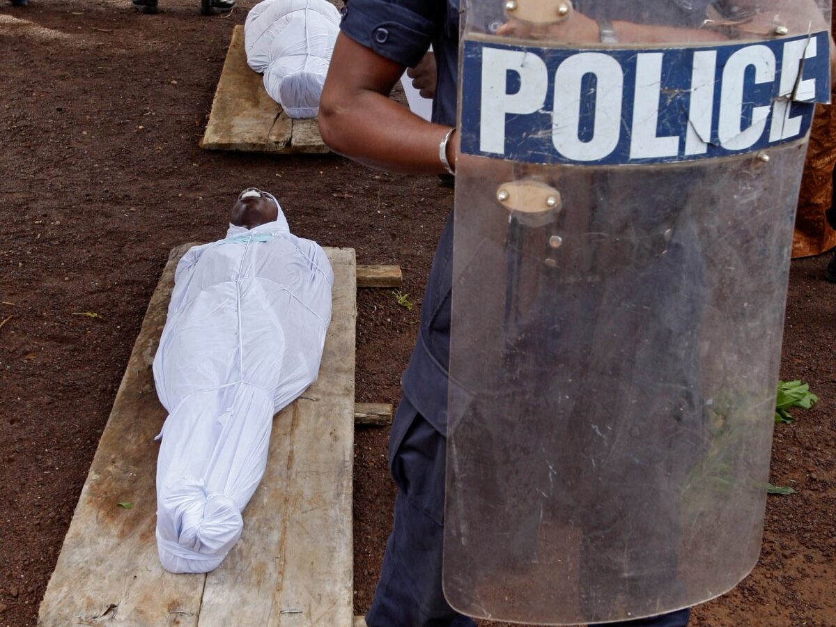In this Friday, Oct. 2, 2009 file photo, a Guinean policeman stands guard beside the bodies of people killed during an opposition rally in Conakry, Guinea on Monday, Sept 28, 2009. A U.S.-based human rights group says the Sept. 28 massacre by Guinean troops of at least 150 people and the rapes of dozens of women at a pro-democracy rally in Guinea were premeditated, and that rapes of kidnapped women continued for days. (AP Photo/Schalk van Zuydam, File)