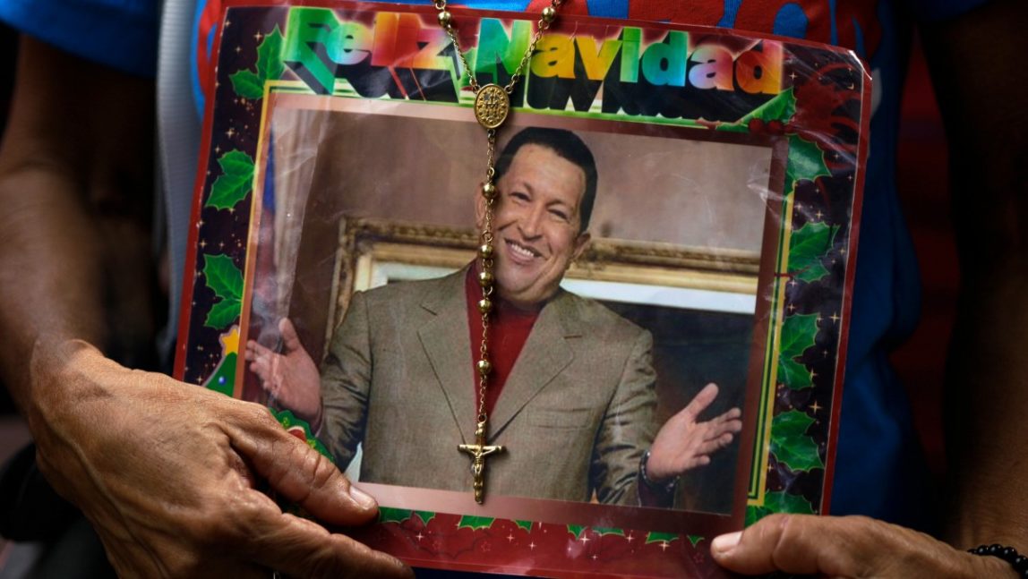 A supporter of Venezuela's President Hugo Chavez holds a picture of him decorated with a rosary and the words in Spanish "Merry Christmas" outside the National Assembly in Caracas, Venezuela, Saturday, Jan. 5, 2013. (AP Photo/Fernando Llano)