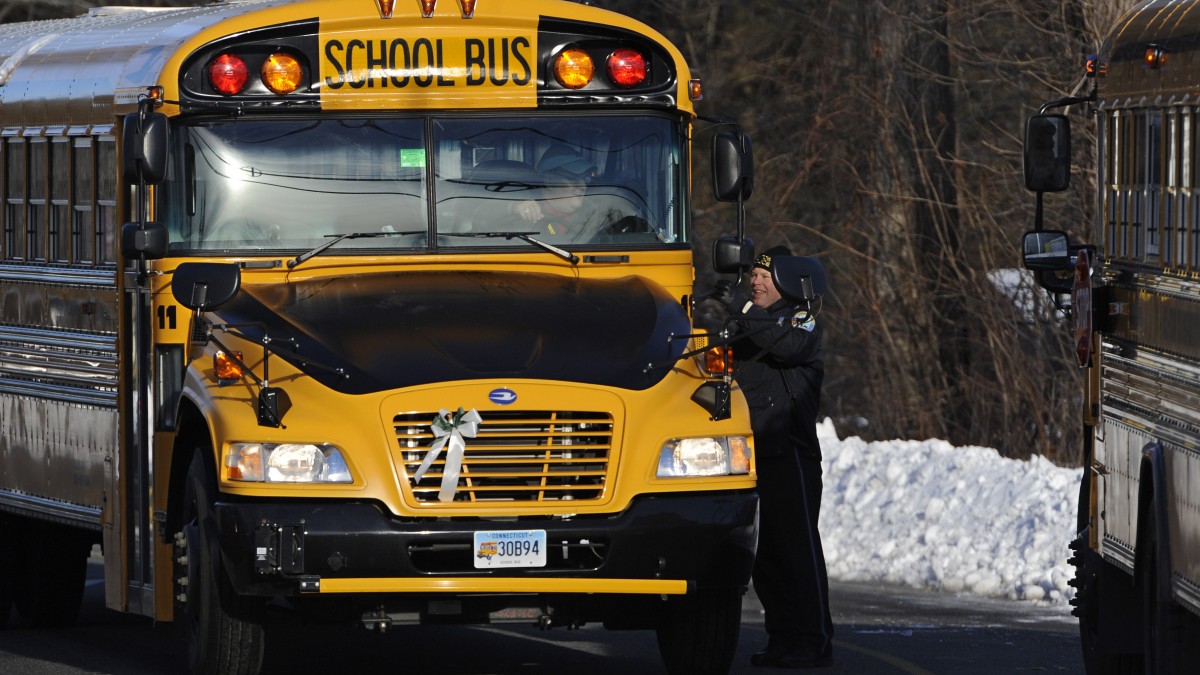 A police officer greets a bus at the entrance to a school on the first day of classes after the holiday break, in Newtown, Conn., Wednesday, Jan. 2, 2013. (AP Photo/Jessica Hill)