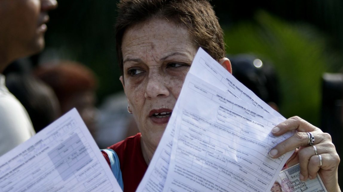 In this Jan. 7, 2013 photo, a woman holds papers after filling out a passport application outside an immigration office in Havana, Cuba. (AP Photo/Franklin Reyes)