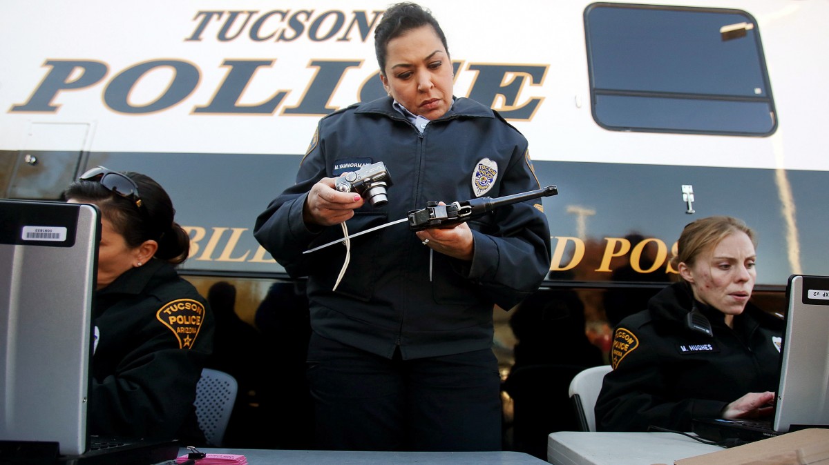 Officer Monica Vannorman, center, photographs a pistol as Officer Merri Hughes, right, logs relinquished weapons at a gun buyback event on Tuesday, Jan. 8, 2013, at the Tucson Police Department Midtown Substation in Tucson, Ariz. (AP Photo/Arizona Daily Star, Mike Christy)