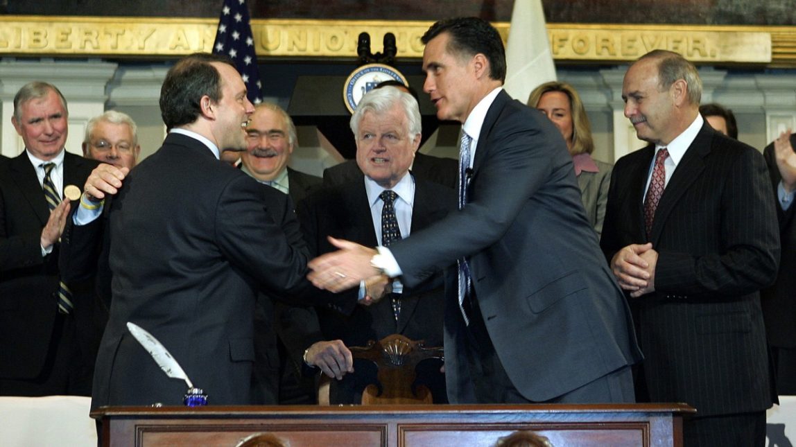 In this April 12, 2006 file photo, Massachusetts Gov. Mitt Romney, right, shakes hands with Massachusetts Health and Human Services Secretary Timothy Murphy after signing into law a landmark bill designed to guarantee that virtually all Massachusetts residents have health insurance at Faneuil Hall in Boston. (AP Photo/Elise Amendola, File)