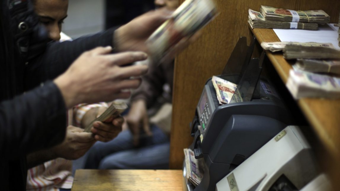 In this Wednesday, Jan. 2, 2013 file photo, Egyptians count money at a currency exchange office in downtown Cairo, Egypt. (AP Photo/Khalil Hamra, File)