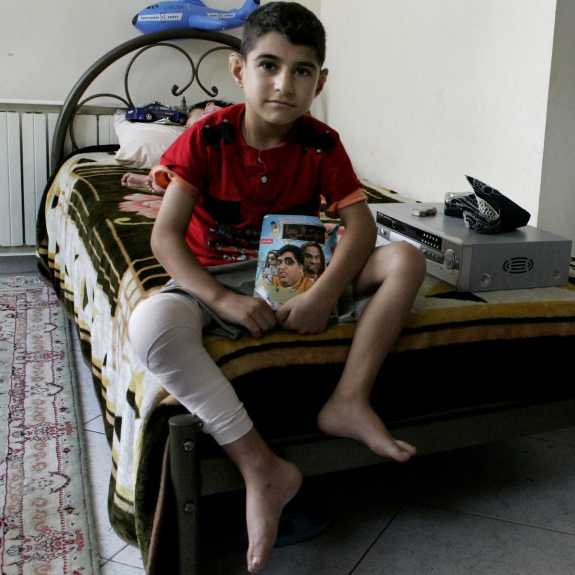 In this Sunday, Aug. 5, 2012 photo, Iranian Milad Rostami, 8, who is suffering from hemophilia, currently recovering from knee surgery, sits on his bed at Iran's Hemophilia Association center, in Tehran, Iran. (AP Photo/Vahid Salemi)
