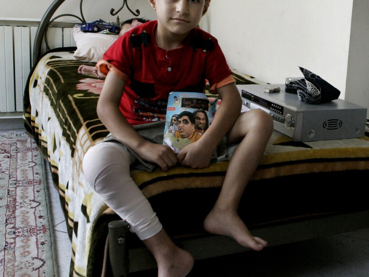 In this Sunday, Aug. 5, 2012 photo, Iranian Milad Rostami, 8, who is suffering from hemophilia, currently recovering from knee surgery, sits on his bed at Iran's Hemophilia Association center, in Tehran, Iran. (AP Photo/Vahid Salemi)