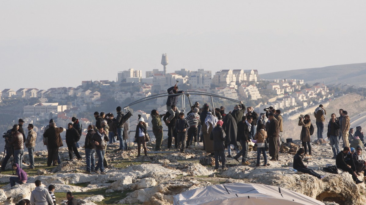 In this Friday, Jan 11, 2013 file photo, Palestinians, together with Israeli and foreign activists, stand near newly-erected tents in an area known as E1 at the settlement of Ma'aleh Adumim, near Jerusalem. (AP Photo/Majdi Mohammed, File)