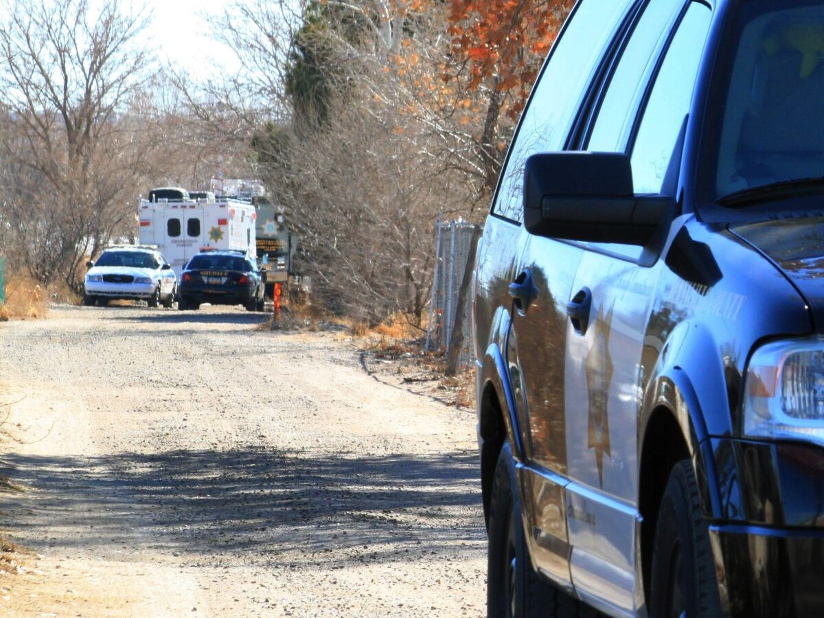A Bernalillo County sheriff's deputy blocks the dirt road that leads to a home where detectives on Sunday, Jan. 20, 2013, were investigating the deaths of five people who were shot to death south of Albuquerque, N.M. (AP Photo/Susan Montoya Bryan)