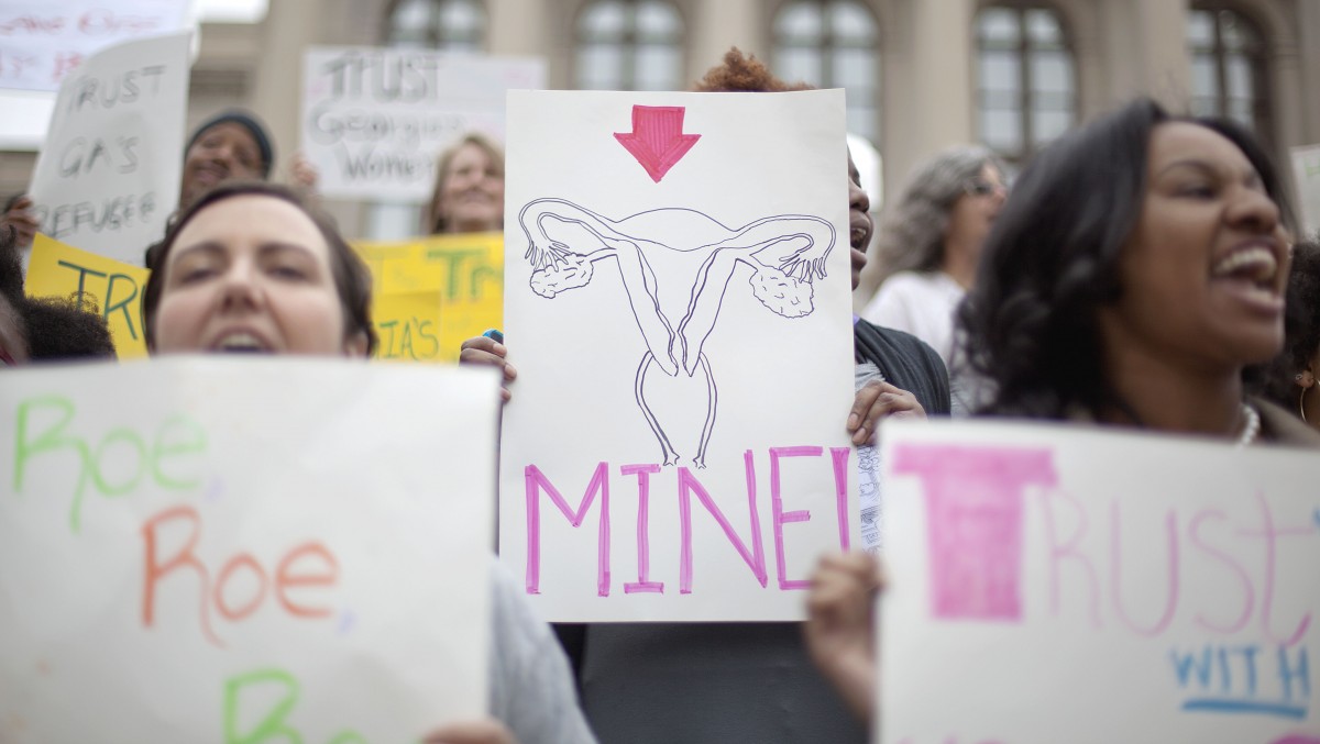 Nichelle Rick-Lewis, center, of Brooklyn, N.Y., holds a sign joining hundreds of people around the Georgia Capitol protesting against two pieces of legislation they say are unfair to women Monday, March 12, 2012, in Atlanta. (AP Photo/David Goldman)