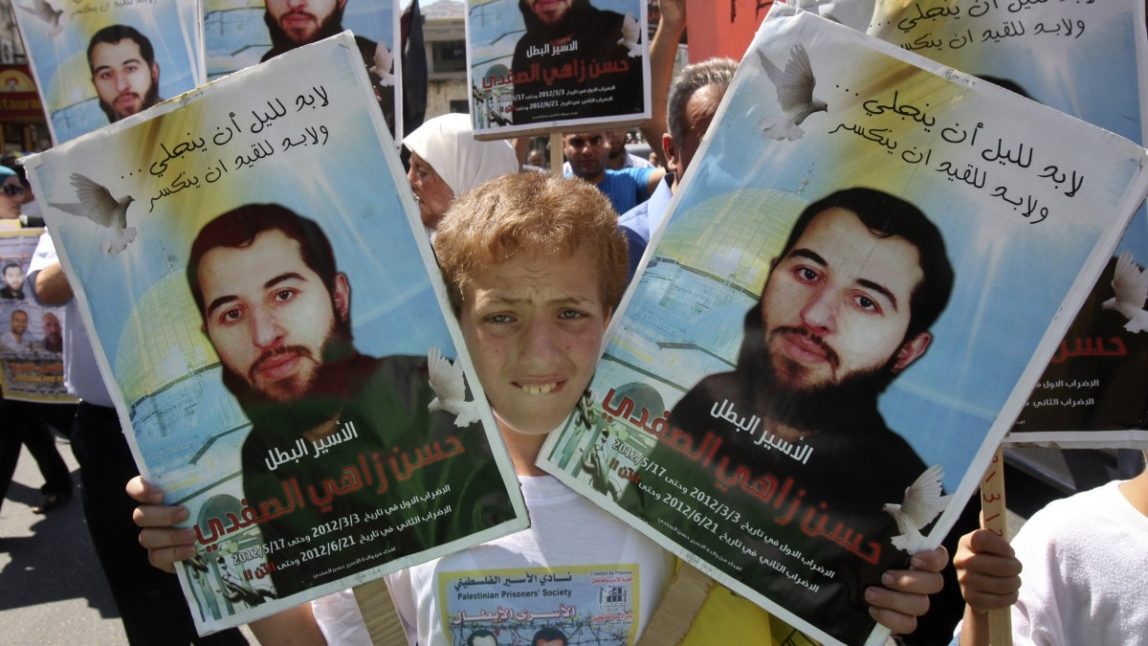 Palestinians hold pictures of Hasan Safadi, who according to relatives has renewed a hunger strike for 87 days, during a protest calling for his release from an Israeli jail, in the West Bank city of Nablus, Saturday, Sept. 15, 2012. (AP Photo/Nasser Ishtayeh)