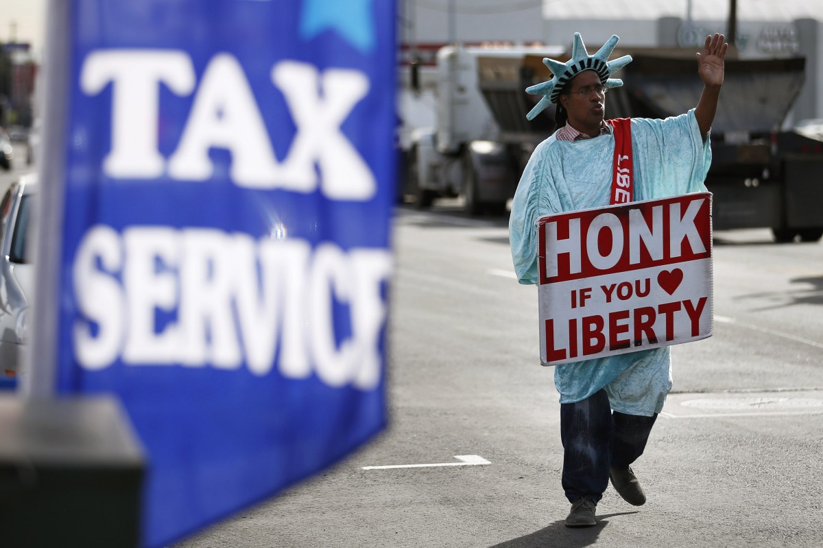 In this Tuesday, Jan. 22, 2013, file photo, dressed as the Statue of Liberty, part-time employee, Zidkijah Zabad, waves to passing motorists while holding a sign to advertise for Liberty Tax Service in Los Angeles. (AP Photo/Jae C. Hong)